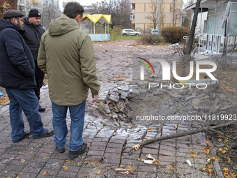 Men stand by the damaged pavement outside a family polyclinic in the Dniprovskyi district affected by an overnight Russian drone attack in K...