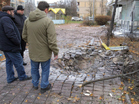 Men stand by the damaged pavement outside a family polyclinic in the Dniprovskyi district affected by an overnight Russian drone attack in K...