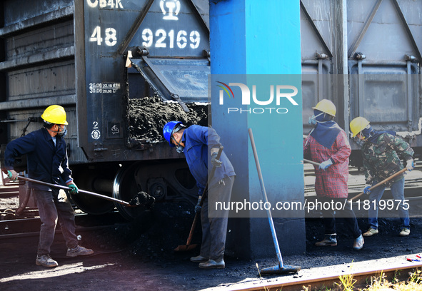 Workers load electric coal that falls on the ground into a car at the railway special line of Jiangxi Coal Reserve Center in Jiujiang, Jiang...