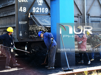 Workers load electric coal that falls on the ground into a car at the railway special line of Jiangxi Coal Reserve Center in Jiujiang, Jiang...