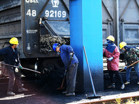 Workers load electric coal that falls on the ground into a car at the railway special line of Jiangxi Coal Reserve Center in Jiujiang, Jiang...