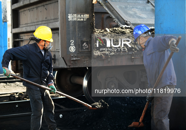 Workers load electric coal that falls on the ground into a car at the railway special line of Jiangxi Coal Reserve Center in Jiujiang, Jiang...