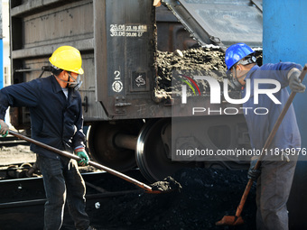 Workers load electric coal that falls on the ground into a car at the railway special line of Jiangxi Coal Reserve Center in Jiujiang, Jiang...