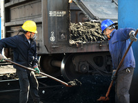 Workers load electric coal that falls on the ground into a car at the railway special line of Jiangxi Coal Reserve Center in Jiujiang, Jiang...