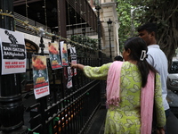 People look at posters while monks of ISKCON (International Society of Krishna Consciousness) and Hindu devotees in Kolkata hold a protest a...