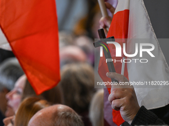 KRAKOW, POLAND - NOVEMBER 24:
One of the party supporters holds a Polish flag and a cross at the event where Karol Nawrocki was nominated as...