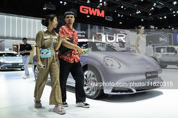 Visitors inspect a GWM ORA electric car displayed at the Thailand International Motor Expo 2024 at the IMPACT exhibition center in Bangkok,...