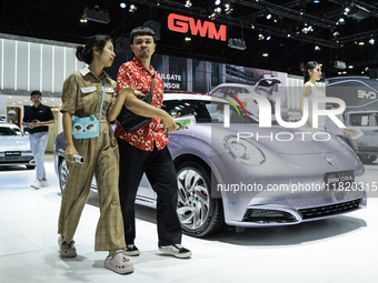 Visitors inspect a GWM ORA electric car displayed at the Thailand International Motor Expo 2024 at the IMPACT exhibition center in Bangkok,...