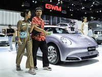 Visitors inspect a GWM ORA electric car displayed at the Thailand International Motor Expo 2024 at the IMPACT exhibition center in Bangkok,...