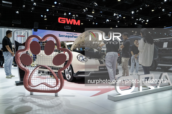 Visitors inspect a GWM ORA electric car displayed at the Thailand International Motor Expo 2024 at the IMPACT exhibition center in Bangkok,...