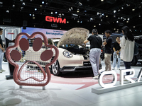 Visitors inspect a GWM ORA electric car displayed at the Thailand International Motor Expo 2024 at the IMPACT exhibition center in Bangkok,...