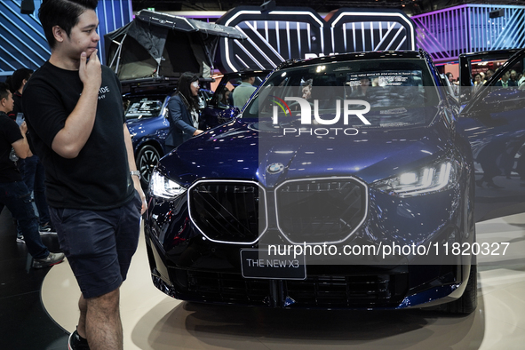 Visitors inspect a BMW X3 electric car displayed at the Thailand International Motor Expo 2024 at the IMPACT exhibition center in Bangkok, T...