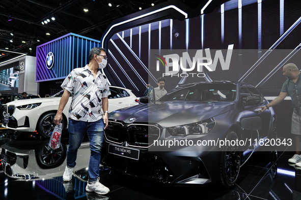 Visitors inspect a new BMW M5 electric car displayed at the Thailand International Motor Expo 2024 at the IMPACT exhibition center in Bangko...