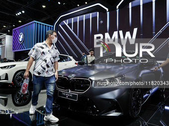 Visitors inspect a new BMW M5 electric car displayed at the Thailand International Motor Expo 2024 at the IMPACT exhibition center in Bangko...