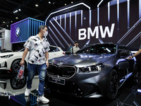 Visitors inspect a new BMW M5 electric car displayed at the Thailand International Motor Expo 2024 at the IMPACT exhibition center in Bangko...