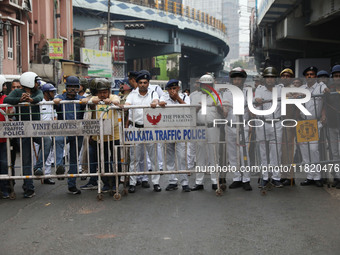 Police personnel block a road while supporters of the ISF (The Indian Secular Front) party shout slogans during a protest march towards the...