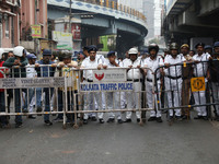 Police personnel block a road while supporters of the ISF (The Indian Secular Front) party shout slogans during a protest march towards the...