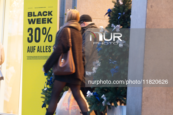 A general view shows shoppers walking out of a retail shop at the city center of Cologne, Germany, on November 29, 2024, during the Black Fr...