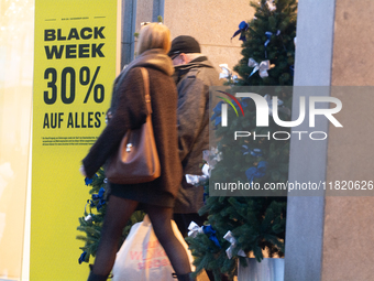 A general view shows shoppers walking out of a retail shop at the city center of Cologne, Germany, on November 29, 2024, during the Black Fr...