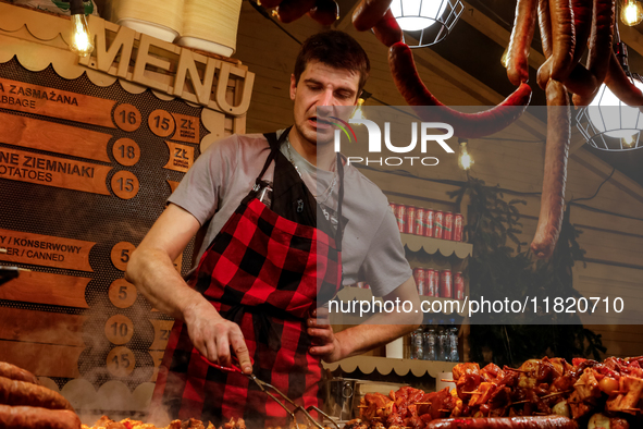 Sellers offer traditional Polish kielbasa and grilled meat as visitors walk the alleys of Krakow's Christmas Market, one of the largest such...