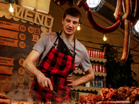 Sellers offer traditional Polish kielbasa and grilled meat as visitors walk the alleys of Krakow's Christmas Market, one of the largest such...