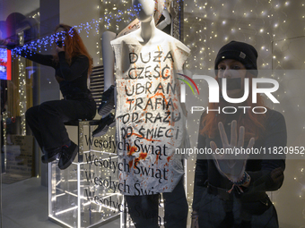 Climate activists with their hands glued to the shop window sit next to a mannequin that wears a message that reads ''The majority of clothe...