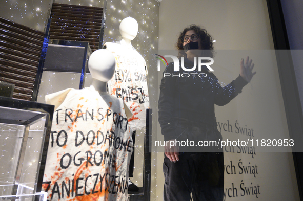 A climate activist with his hand glued to a shop window stands next to a mannequin that bears a message reading ''Transport is an additional...