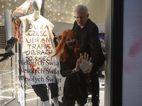 A member of the shop security tries to remove a climate activist as her hand is glued to the shop window. The mannequin bears a message that...