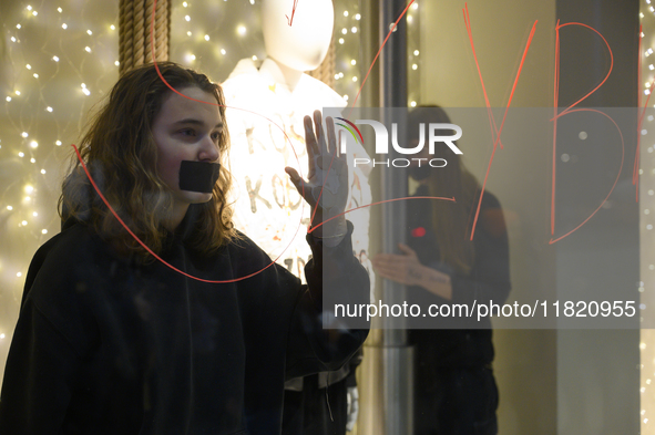 Climate activists with their hands glued to a shop window take part in a protest against fast fashion in Warsaw, Poland, on November 29, 202...