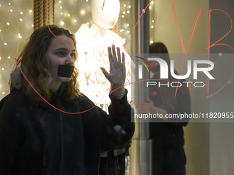 Climate activists with their hands glued to a shop window take part in a protest against fast fashion in Warsaw, Poland, on November 29, 202...