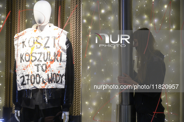 A climate activist participates in a protest as she stands next to a mannequin that bears a message that reads ''The cost of a t-shirt is 2,...