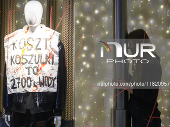 A climate activist participates in a protest as she stands next to a mannequin that bears a message that reads ''The cost of a t-shirt is 2,...