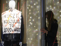 A climate activist participates in a protest as she stands next to a mannequin that bears a message that reads ''The cost of a t-shirt is 2,...