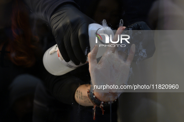 A police officer removes the glued hand of a climate activist during a protest against fast fashion in Warsaw, Poland, on November 29, 2024....