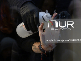 A police officer removes the glued hand of a climate activist during a protest against fast fashion in Warsaw, Poland, on November 29, 2024....