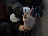 A police officer removes the glued hand of a climate activist during a protest against fast fashion in Warsaw, Poland, on November 29, 2024....