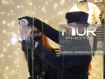 A police officer removes the glued hand of a climate activist during a protest against fast fashion in Warsaw, Poland, on November 29, 2024....