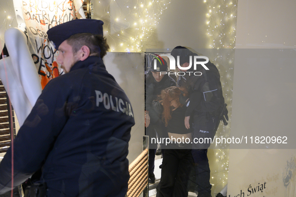 Police officers detain a climate activist during a protest against fast fashion in Warsaw, Poland, on November 29, 2024. Climate activists f...