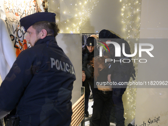 Police officers detain a climate activist during a protest against fast fashion in Warsaw, Poland, on November 29, 2024. Climate activists f...