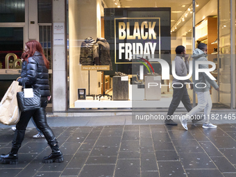 Promotional signage advertises up to 70% off for Black Friday at a clothing store in Bari, Italy, on November 29, 2024. The image highlights...