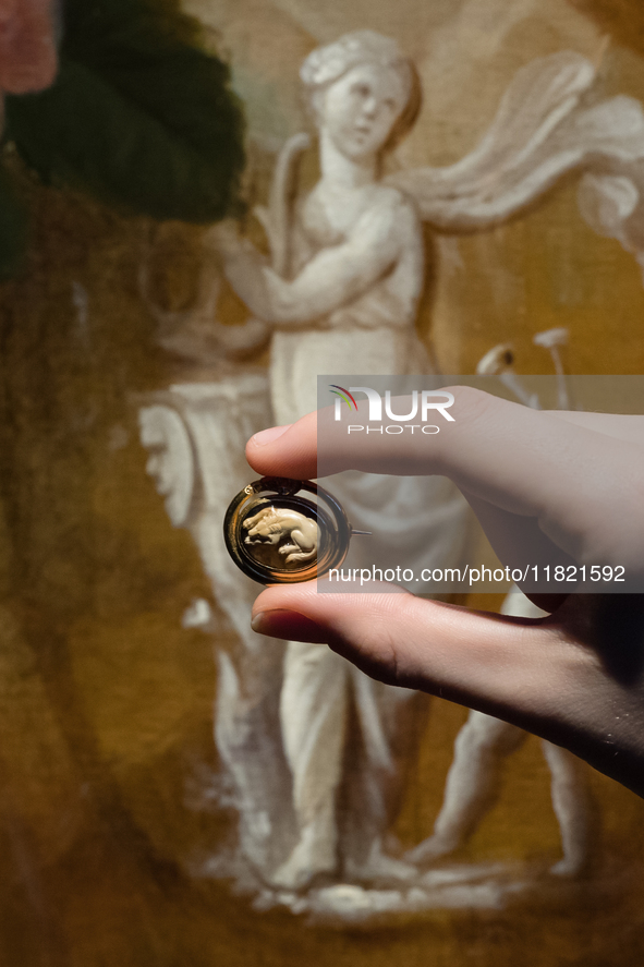 LONDON, UNITED KINGDOM - NOVEMBER 29, 2024: A staff member holds a brooch titled 'A Roman Agate Cameo with a Dog', set in 19th century, (est...