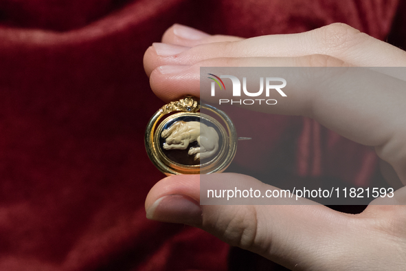 LONDON, UNITED KINGDOM - NOVEMBER 29, 2024: A staff member holds a brooch titled 'A Roman Agate Cameo with a Dog', set in 19th century, (est...