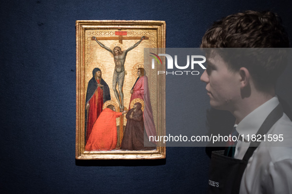 LONDON, UNITED KINGDOM - NOVEMBER 29, 2024: An art handler looks at 'The Crucifixion with the Virgin, Mary Magdalene, John the Evangelist an...