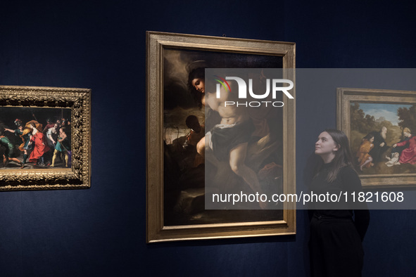 LONDON, UNITED KINGDOM - NOVEMBER 29, 2024: A staff member looks at a painting by Luca Giordano (Naples 1634-1705) titled 'The Martyrdom of...