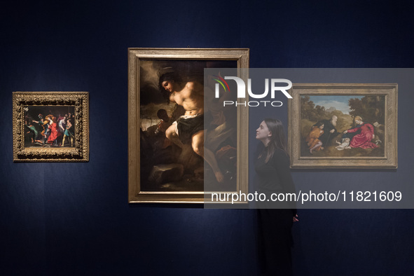 LONDON, UNITED KINGDOM - NOVEMBER 29, 2024: A staff member stands next to paintings by Alessandro Turchi, Called L'orbetto (Verona 1578-1649...