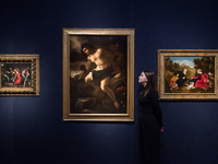 LONDON, UNITED KINGDOM - NOVEMBER 29, 2024: A staff member stands next to paintings by Alessandro Turchi, Called L'orbetto (Verona 1578-1649...