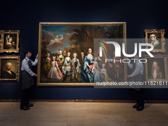 LONDON, UNITED KINGDOM - NOVEMBER 29, 2024: Art handlers hold a painting by James Maubert (Ireland 1666-1746 London) titled 'Group portrait...