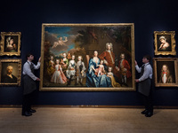 LONDON, UNITED KINGDOM - NOVEMBER 29, 2024: Art handlers hold a painting by James Maubert (Ireland 1666-1746 London) titled 'Group portrait...