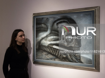 LONDON, UNITED KINGDOM - NOVEMBER 29, 2024: A staff member looks at a painting 'Dune VI' by H.R. Giger estimate: GBP40,000 - 60,000 during a...