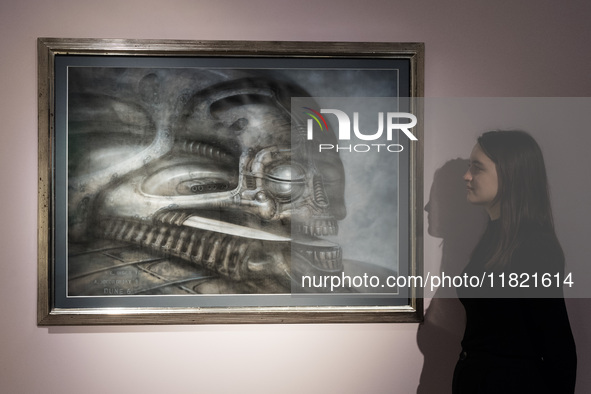 LONDON, UNITED KINGDOM - NOVEMBER 29, 2024: A staff member looks at a painting 'Dune VI' by H.R. Giger estimate: GBP40,000 - 60,000 during a...